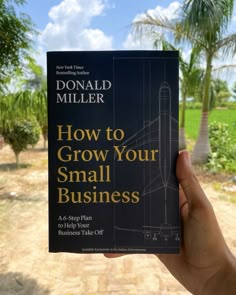 the book how to grow your small business by donald miller is held in front of a palm tree