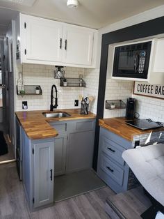 a small kitchen with wooden counter tops and white cabinets, along with a gray couch