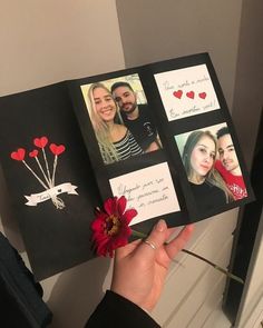 a hand holding an open photo book with pictures and hearts on it, next to a red flower