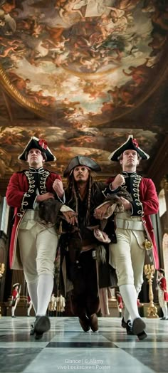 three men dressed in pirate costumes standing next to each other under a painting on the ceiling