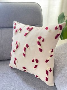 a white pillow with candy canes on it sitting on a blue couch next to a potted plant