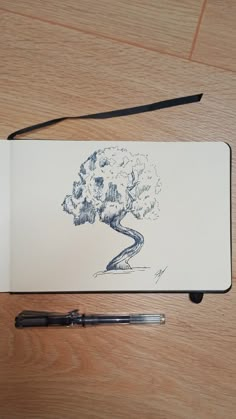 a pen sitting on top of a piece of paper next to a drawing of a tree