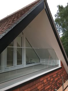 an open window on the side of a brick building with a roof and shingles