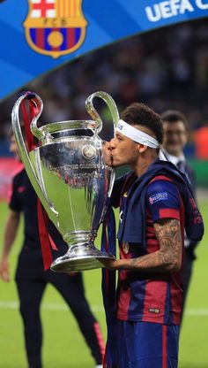 the soccer player is kissing the trophy on the field