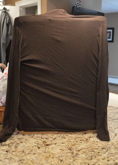 the back of a chair is covered with a brown cloth and sits on a kitchen counter