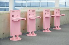 four pink electronic kiosks lined up against a wall