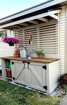 an outdoor kitchen with potted plants on the counter and flowers hanging from the roof