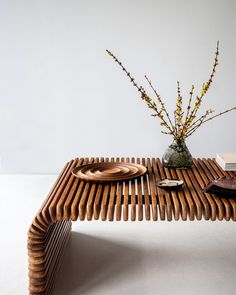 a wooden table with plates on it and flowers in a vase next to the table