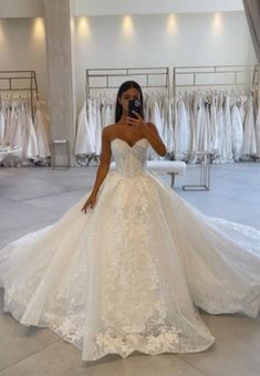 a woman taking a selfie in her wedding dress at the bridal gown shop