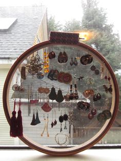 there are many earrings hanging on the window sill in front of the house with it's reflection