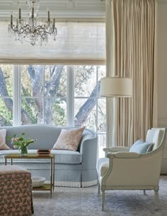 a living room filled with furniture and a chandelier hanging from the ceiling next to a window