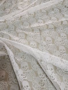 a white lace with skulls on it is laying next to a piece of fabric that has been cut in half