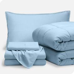 a bed with blue sheets and pillows next to each other on a white background,