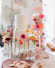 a table topped with a tall white cake covered in flowers