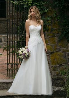 a woman standing in front of a gate wearing a wedding dress