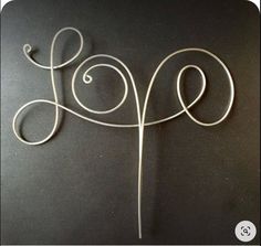 a piece of wire that is on top of a black surface with the word love written in it