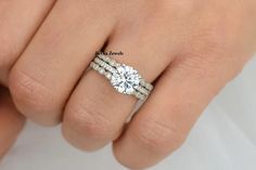 a woman's hand with a diamond ring on top of her wedding band,