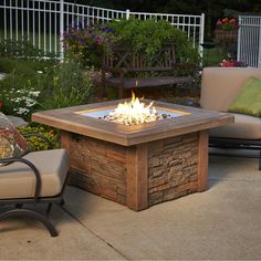 a fire pit sitting on top of a patio next to two chairs and a table