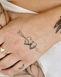 a woman's hand with tattoos on it and a ring in her left hand