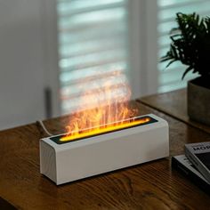 a white box sitting on top of a wooden table next to a potted plant