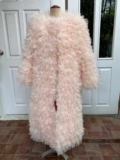 a pink fur coat sitting on top of a mannequin's head in front of a door