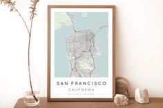 a framed map of san francisco, california is displayed on a shelf next to a vase with flowers