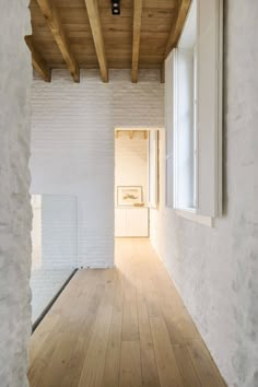 an empty room with wood flooring and white bricks on the walls, along with wooden beams