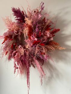 an arrangement of pink and red flowers on a white wall