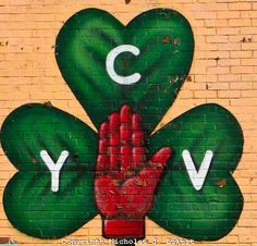 a brick wall with a painted clover and the letter y on it's side