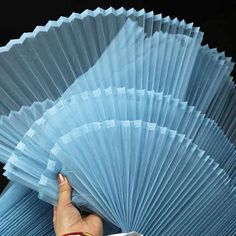 a person holding a large blue fan in their hand