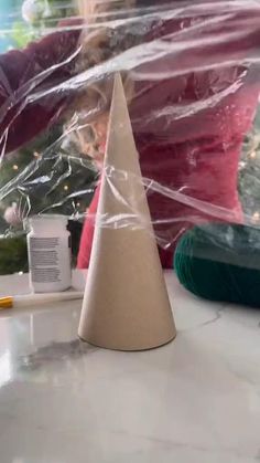 a woman sitting at a table in front of a christmas tree wearing a plastic wrap around her head