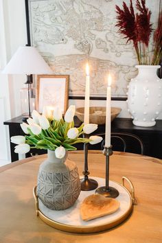 a vase with flowers and two candles on a table