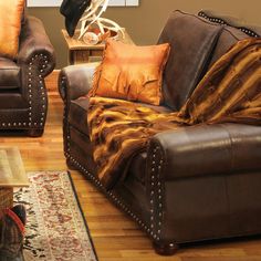 a living room with two brown couches and a rug on the wooden flooring