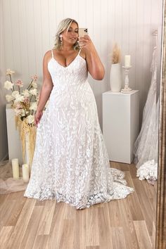 a woman taking a selfie in front of a mirror wearing a white wedding dress