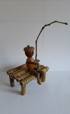 a figurine sitting on top of a bamboo bench next to a tree branch