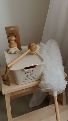 a white bucket and brush sitting on a wooden table next to a package of toilet brushes