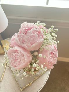 some pink flowers are in a glass vase on a table next to a lamp and window