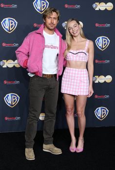 a man and woman standing next to each other in front of a blue wall with logos on it