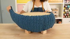 a woman sitting in front of a knitted bowl