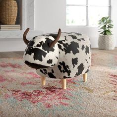 a cow shaped stool sitting on top of a rug