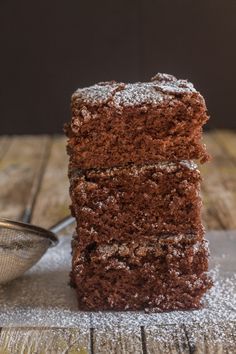 three pieces of chocolate cake are stacked on top of each other with powdered sugar