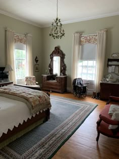 a bedroom with a bed, chair, dresser and mirror in the middle of it