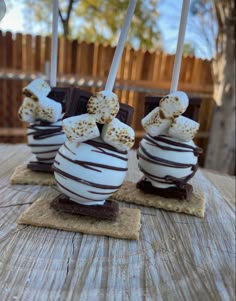 three chocolate covered desserts sitting on top of a wooden table