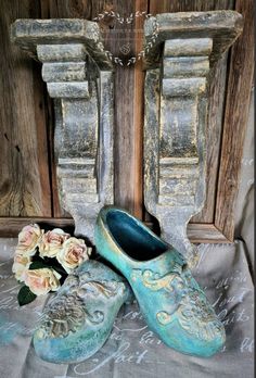 there is a pair of blue shoes next to some flowers on a table with an old wooden door in the background