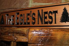 a wooden sign that says the hege's nest with pine trees on it