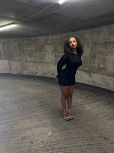 a woman standing in an empty parking garage with her hands on her hips and looking at the camera