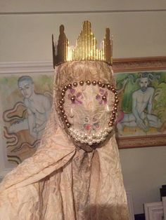 a statue with a crown on it's head in front of paintings and pictures