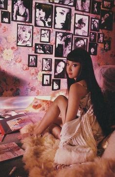 a woman sitting on top of a bed next to pictures