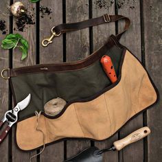 a tool bag sitting on top of a wooden table next to gardening tools and plants