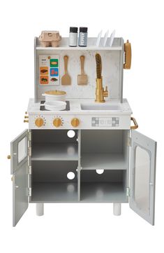 a toy kitchen with white cabinets and gold accessories on the top shelf, including utensils